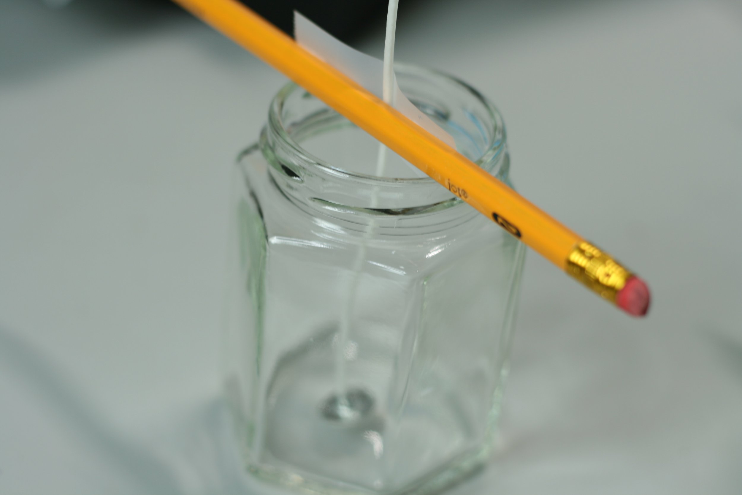pencil centering a wick for the candle wax