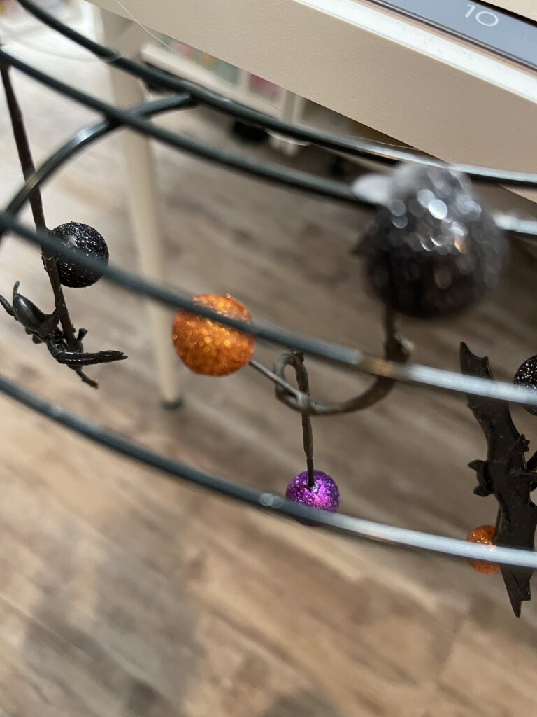 wire wreath form with small halloween type ornaments hanging from the wire