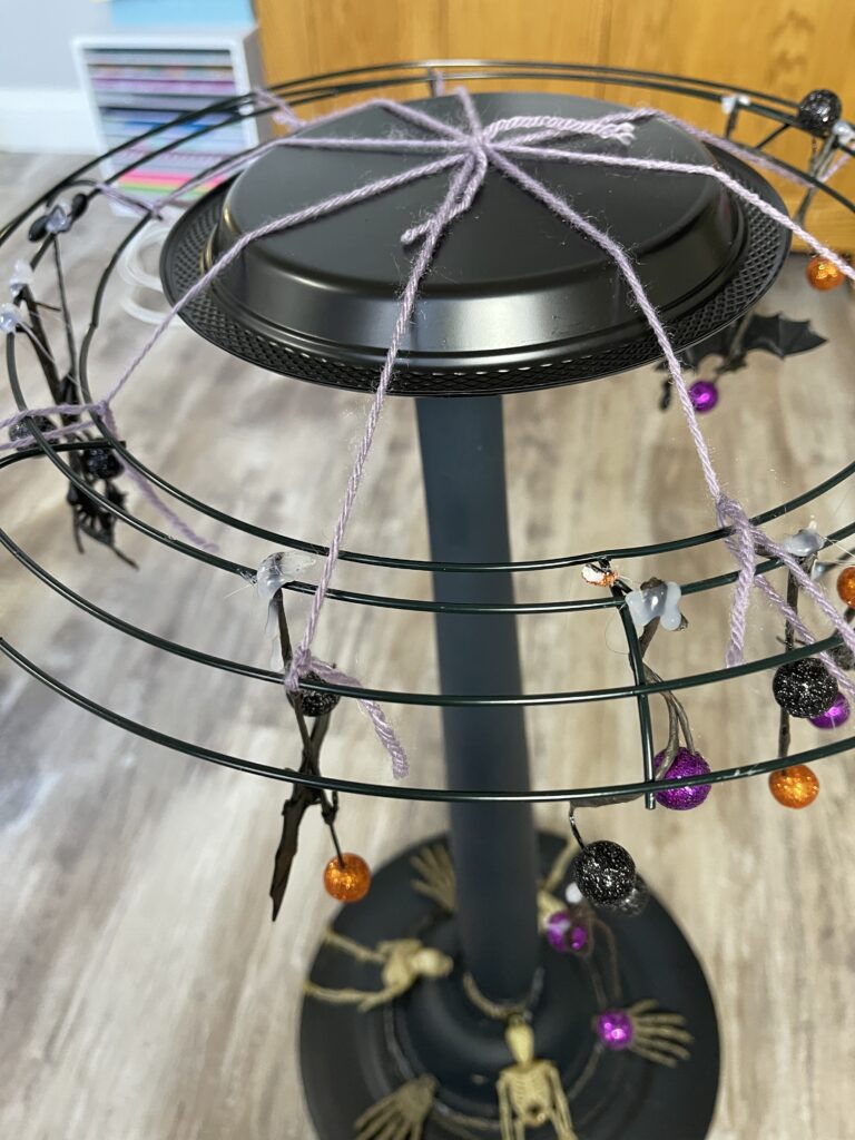 top of a black diy lamp with purple yarn holding a wire wreath form on top