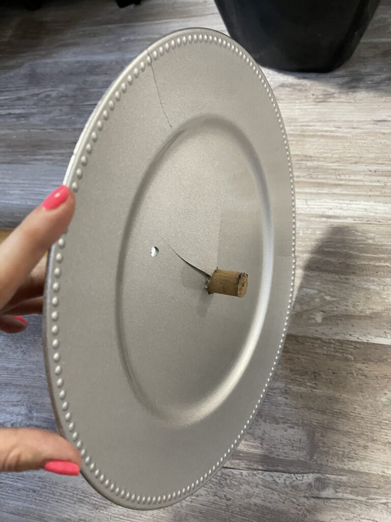 Silver, plastic charger plate with hole in the center and small wooden dowel sticking out